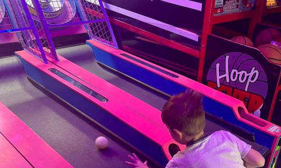 A littl boy rolling a ball to score in an arcade game