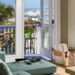 Looking beyond a soft teal-colored sofa in the forground, through the French doors to the private deck with a view of the Atlantic
