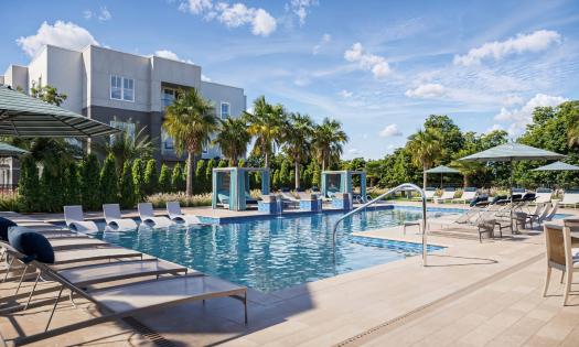 The pool area includes lungers, cabanas, and tables with umbrellas