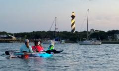 An LED kayak on the water with the Lighthouse in the distance