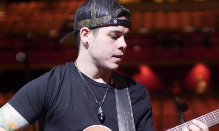 Country performer Nathan Allen in a backwards ballcap singing into microphone