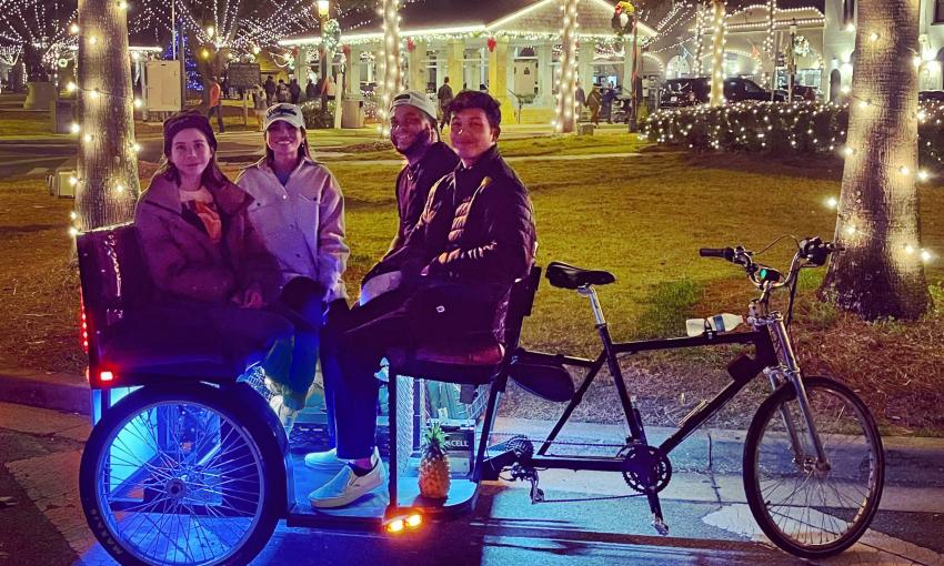 A Pineapple tour pedicab taking passengers past the Plaza in St. Augustine during Nights of Lights