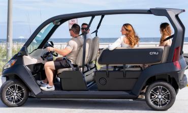 Customers riding by the beach in a golf cart